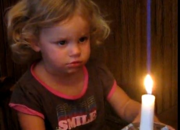 Девочка пытается задуть свечу на торте